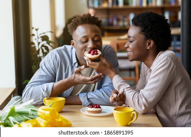 Lovely Black Woman Feeding Tasty Berry Tartlet To Her Boyfriend At Cozy City Cafe. Affectionate African American Couple Having Dessert And Coffee At Restaurant, Enjoying Their First Date