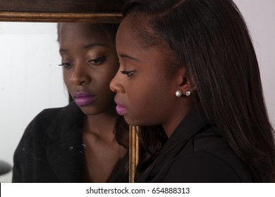 Lovely Black Woman Looking Thoughtfully Into A Mirror