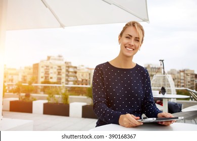 Lovely business woman with smile is sitting with touch pad in comfortable restaurant during recreation time, happy female student works on digital tablet and relaxes in coffee shop after university