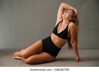 Lovely Caucasian female in her black underwear sitting on the floor