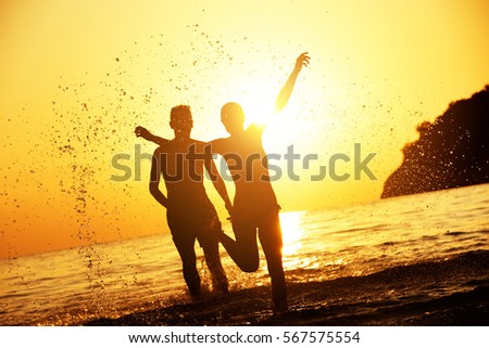 Lovely couple at the beach runs to sunset. Tropical sea travel