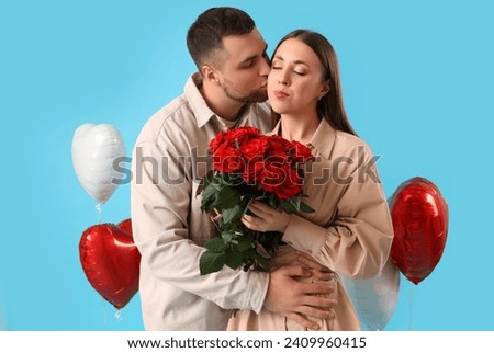 Lovely couple with bouquet of roses and heart-shaped balloons on blue background. Valentine's Day celebration