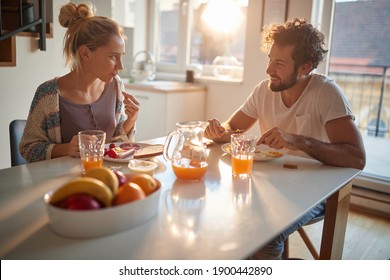 Lovely couple having breakfast together in the kitchen - Shutterstock ID 1900442890