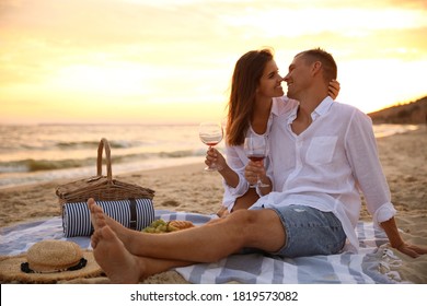 Lovely Couple Having Romantic Picnic On Beach At Sunset