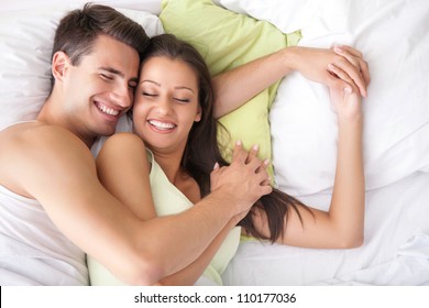 Lovely couple hugging on their bed at home