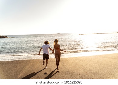 Lovely couple playing on a sandy beach together, having fun, sunset beautiful time. Real people lifestyle, holidays concept.