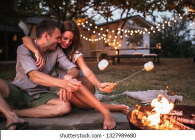 Lovely couple roasting marshmallows in the backyard - Powered by Shutterstock