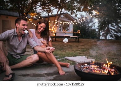 Lovely couple roasting marshmallows in a backyard
