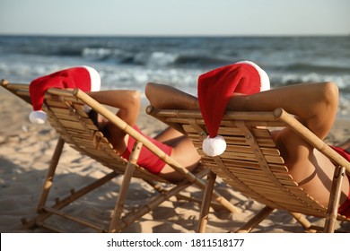 Lovely couple with Santa hats relaxing on deck chairs at beach. Christmas vacation - Powered by Shutterstock