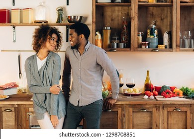 Lovely couple standing together in cozy kitchen, looking at each other, copy space - Shutterstock ID 1298708851