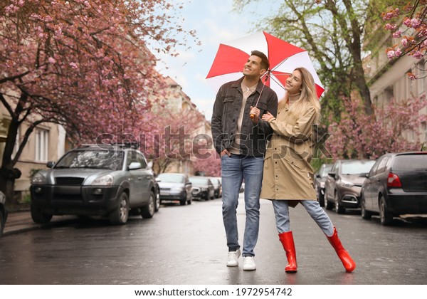 Lovely couple\
with umbrella walking on spring\
day