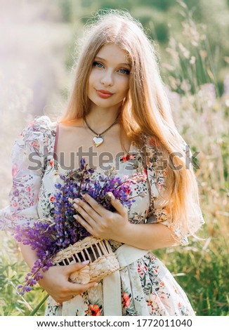 Lovely cute woman in lupine field, sunny day, freedom concept