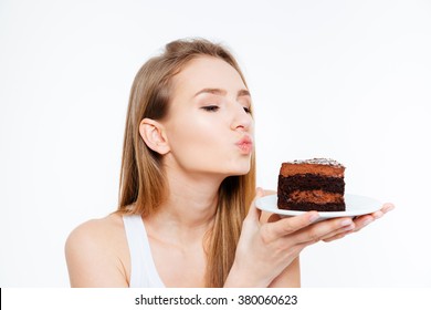 Lovely cute young woman holding piece of chocolate cake and sending a kiss over white background