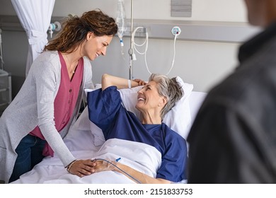 Lovely daughter and careful son visiting sick mother in hospital. Senior patient smiling in conversation with her family while hospitalized. Daughter visiting her old mother lying in bed at hospital. - Shutterstock ID 2151833753
