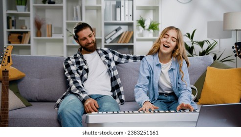 Lovely daughter play piano with father in the living room with happy moment. Child learning playing piano from her father. Weekend activity happy family lifestyle concept - Powered by Shutterstock