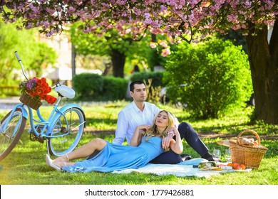 Lovely Day. Woman And Man Lying In Park And Enjoying Day Together. Valentines Day Picnic. Romantic Picnic In Park. Couple Date On Blanket Under Sakura Flowers. Camping. Happy Couple In Love.