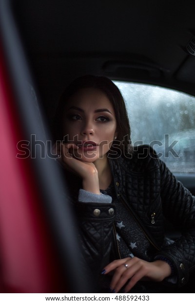 Lovely\
dreaming woman in car. Rainy weather\
outside.
