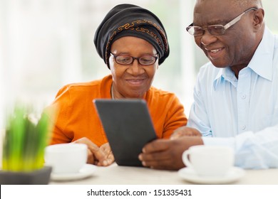 lovely elderly african couple using tablet computer at home