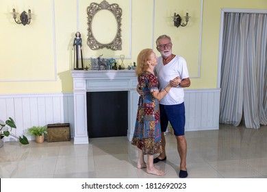 Lovely Elderly Couple Enjoys Romantic Dance To Celebrate Anniversary At Home. Senior Couple Doing Exercise By Dancing For Health. Elderly Wife And Husband Share Happy Time Together With Dance. 