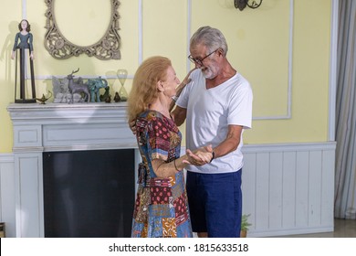 Lovely Elderly Couple Enjoys Romantic Dance To Celebrate Anniversary At Home. Senior Couple Doing Exercise By Dancing For Health. Elderly Wife And Husband Share Happy Time Together With Dance. 