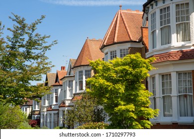 Lovely English Edwardian residential houses in a row with spectacular wooden bay casement windows. Front view on the properties from the street with green trees on a sunny day. London, UK 21/04/2020 - Powered by Shutterstock