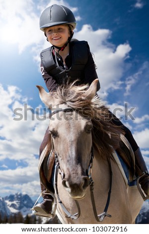 Lovely equestrian - little girl is riding a horse, Dolomites mountain in the background