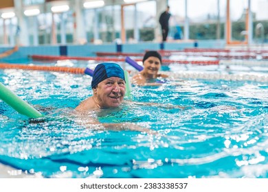 lovely European couple having swimming lesson with swim noodles in the indoor pool. High quality photo - Powered by Shutterstock