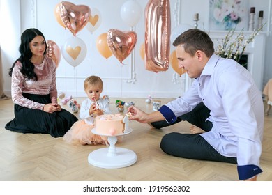 Lovely Family Celebrating Birthday Of Daughter With Sweets, Cake And Balloons. Kids Birthday Party. Mom, Dad And Baby Girl Have Fun Together. Cake Smash, One Year Birthday Concept. Messy Crumb Cake