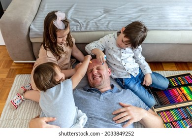 Lovely family having fun together at home  Photo one son   two daughters drawing their father face   having fun at the house during the day  A happy family spends time playing together 