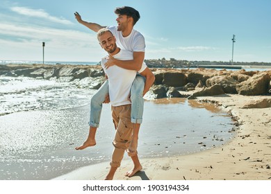 Lovely Gay Couple On Piggyback Ride At The Beach.