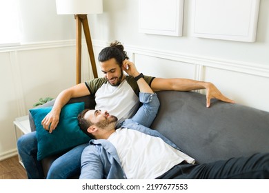 Lovely gay happy man cuddling with his partner while resting together on the sofa during a romantic relaxing time - Powered by Shutterstock