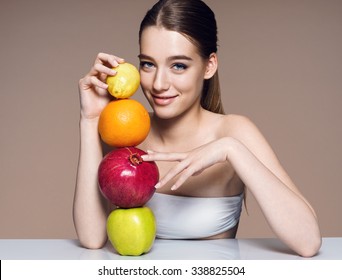 Lovely girl with fruits mix, natural organic raw fresh food concept  / portrait of girl with fruits mix on the table over beige backdrop