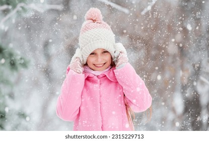 Lovely girl grinning widely and happily in the winter forest, holding her hat - Shutterstock ID 2315229713