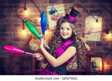 Lovely girl in a top cap with clown make-up juggles behind the scenes of the circus