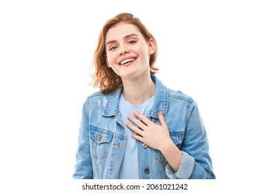 Lovely good-natured red-haired girl student in blue denim jacket with charming smile and friendly expression, holding hands on heart, wanting to show her love and sympathy On white background - Powered by Shutterstock