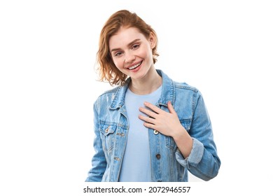 Lovely good-natured red-haired girl student in blue denim jacket with charming smile and friendly expression, holding hands on her heart wanting to show her love and sympathy On  white background - Powered by Shutterstock