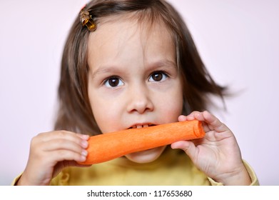 lovely happy little girl eating a carrot