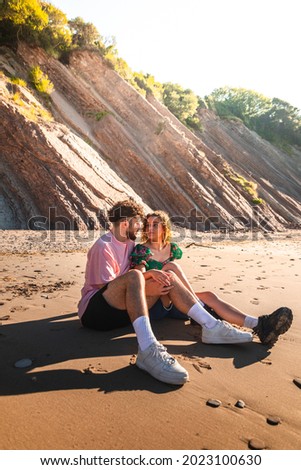 Lovely heterosexual couple on a rocky beach embracing and kissing at the Basque Country.