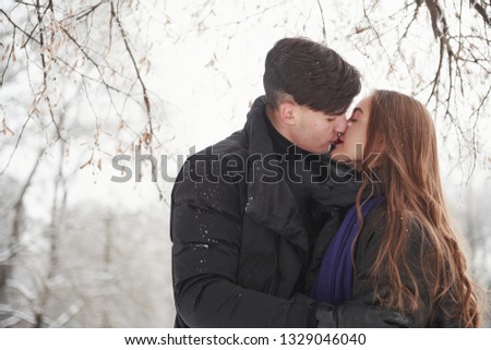 Lovely kisses. Gorgeous young couple have good time together in snowy forest.