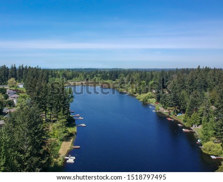 Lovely Lake Holm Water Access Site in springtime with the surrounding forest and homes and the sky and clouds in Auburn Washington.