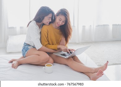 Lovely Lesbian Couple Together Concept. Couple Of Young Women Using Computer Laptop On Bed. LGBT Concept.