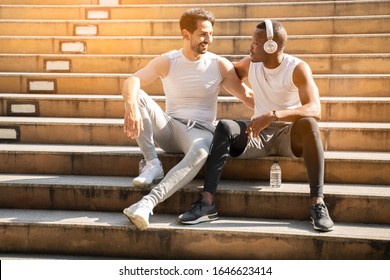 Lovely LGBT Gay Couple Exercise And Relax Concept.young Bearded Man With African Black Friend Sitting On Stair Step After Running Workout In City.Sport And Healthy Lifestyle In Town.