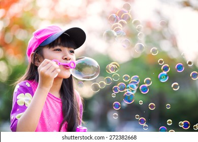 Lovely little asian girl blowing soap bubbles, Outdoor portrait