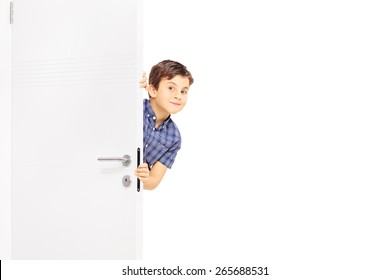 Lovely Little Boy Sneaking A Peek Behind A Door And Looking At The Camera Isolated On White Background