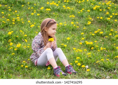 Lovely little girl playing in the spring field full of dandelions