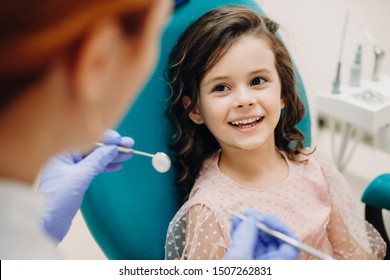 Lovely little kid smiling while talking with the pediatric dentist after doing a tenth examination in a pediatric stomatology.