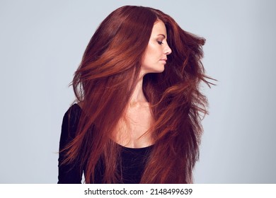 Lovely Luscious Locks. Studio Shot Of A Young Woman With Beautiful Red Hair Posing Against A Gray Background.