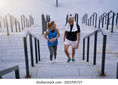 Lovely Mature Couple, Man And Woman In Sportswear Smiling At Each Other, Walking Up The Stairs After Training Together Outdoors