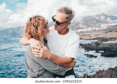 Lovely mature and romantic senior couple embrace each other on the seashore looking into each other's eyes, two embraced people stay together expressing love and tenderness - Powered by Shutterstock