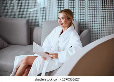 Lovely merry woman holding the beauty salon service menu and price list in her hands - Powered by Shutterstock